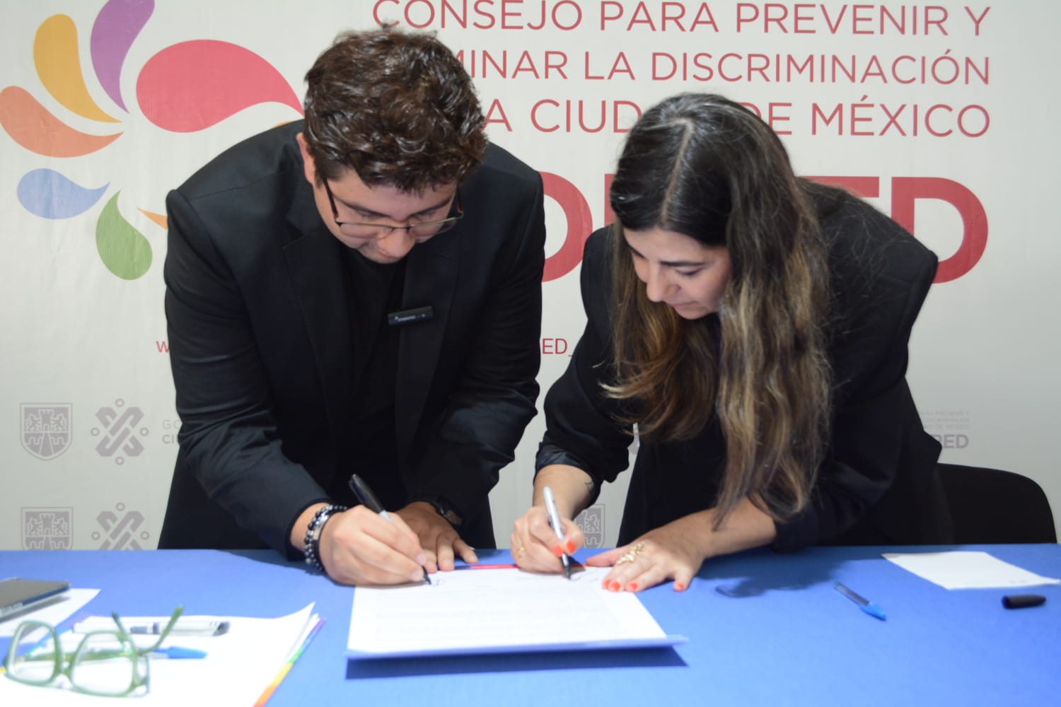 Foto de la firma de la titular del Copred, Geraldina González de la Vega y el Director General de Pride Connection México, firmando el acuerdo